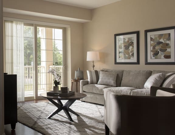 a living room with a couch and a chair and a door to a balcony