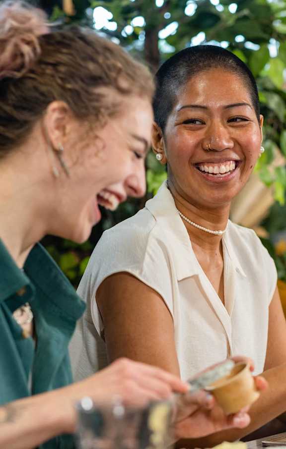 Two women laughing while eating food.at Dwell at Greenridge, North Charleston, SC, 29406