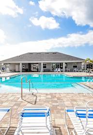 A pool with blue and white lounge chairs in front of a building.