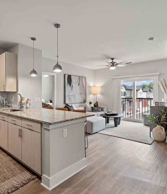 A modern kitchen with a large island and a dining area in the background.