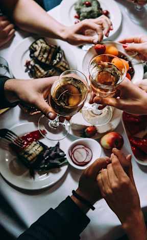 A group of people toasting with drinks at a dinner table.