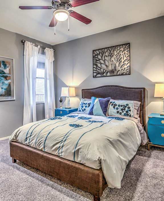 A bedroom with a bed, nightstand, and a ceiling fan.