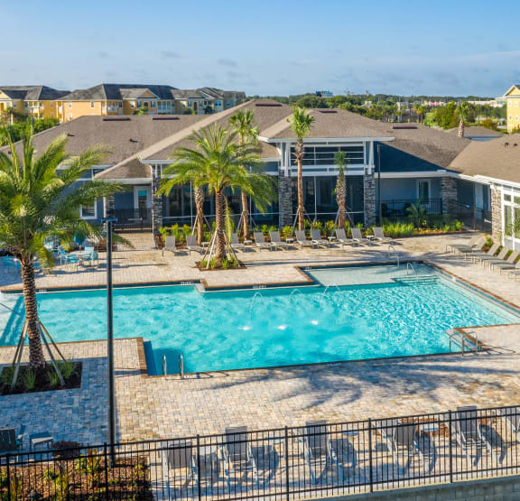 a swimming pool with chairs and a building in the background