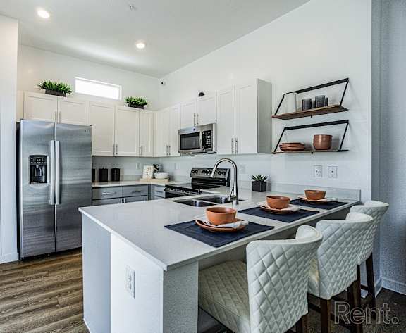 A kitchen with a white island and white chairs.