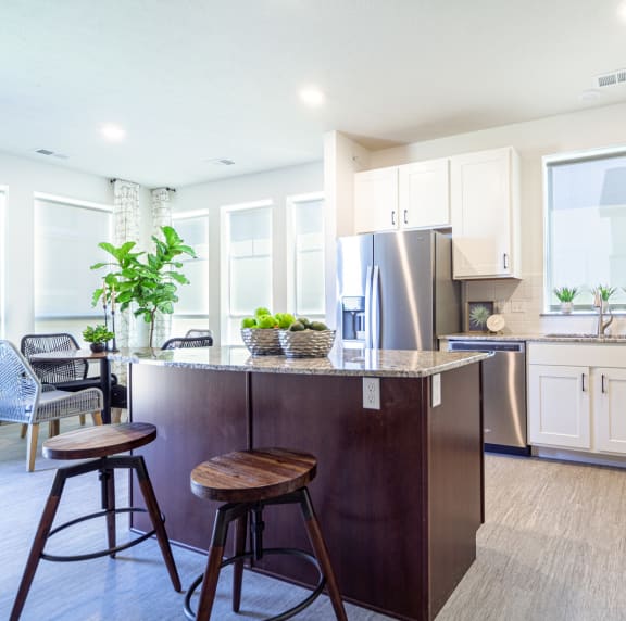 a kitchen with white cabinets and stainless steel appliances and a bar with stools