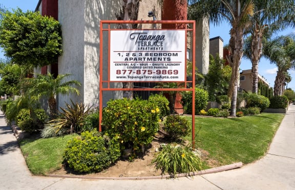 a sign in front of a building with palm trees