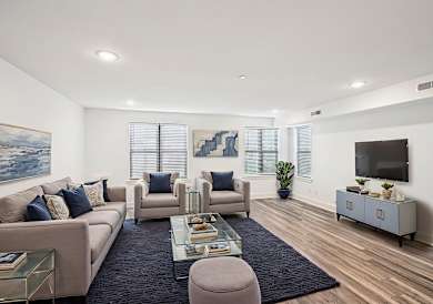 A living room with a sofa, armchairs, a coffee table, and a television.