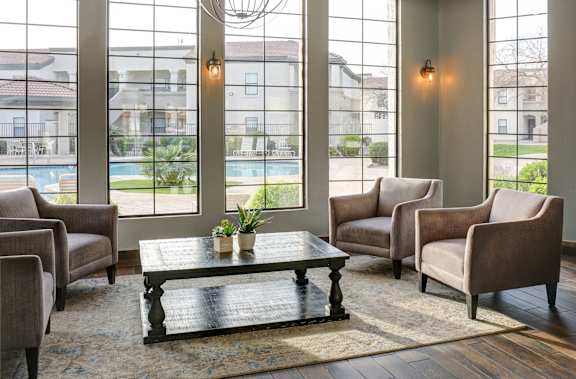 A living room with a large window and a view of a pool and houses.