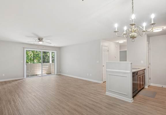 A room with a wooden floor, a ceiling fan, and a chandelier.