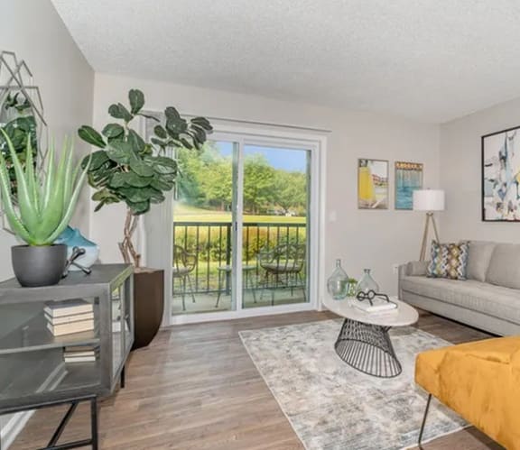 a living room with a couch and a door to a balcony at Village 1373, Greensboro, 27455