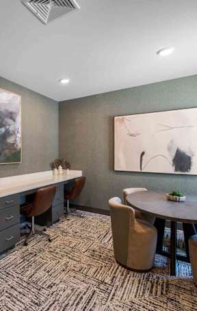 A room with chairs around a table, a countertop for working on a computer, and art hanging on the wall in the background
