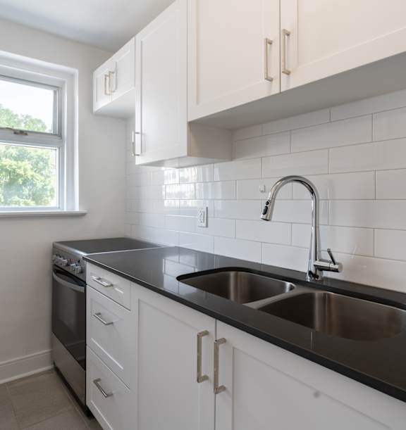 the living room and kitchen of an apartment with wood floors and white cabinets at 391 Sherbourne Apartments, Ontario