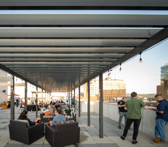 a group of people sitting in chairs under awning on a patio