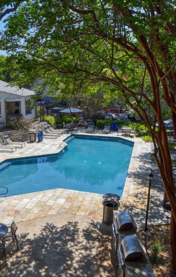 a large deck with chairs and umbrellas next to a pool