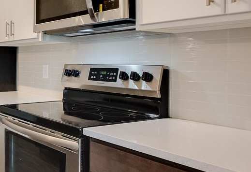 A kitchen with an oven, microwave, and island with a sink