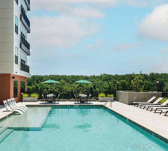 Sparkling swimming pool with sun tanning ledge, lounge chairs and two covered bistro tables  at Chapter at the Streets of St Charles, Missouri, 63303