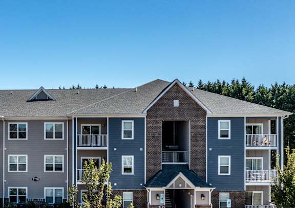 A large apartment complex with multiple buildings and cars parked in the lot.