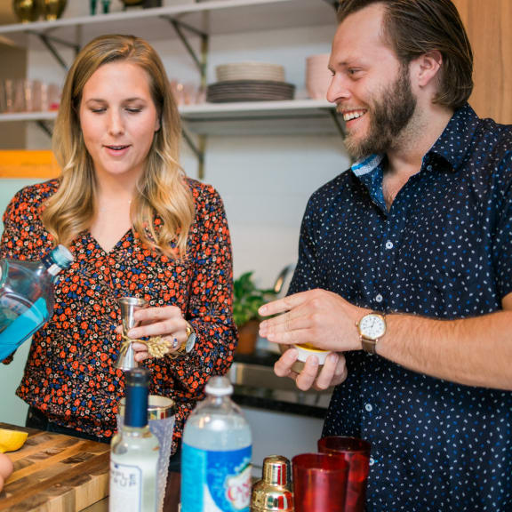 a man and a woman standing at a bar preparing drinks