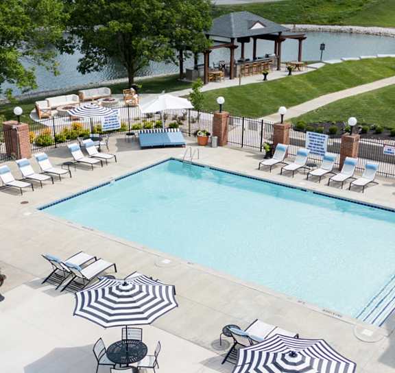 A large outdoor swimming pool surrounded by lounge chairs and umbrellas. at Sundance Apartments, Indianapolis, Indiana, 46237