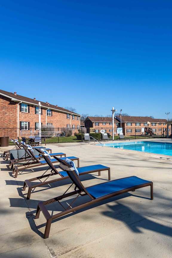 A pool with sun loungers and a building in the background.