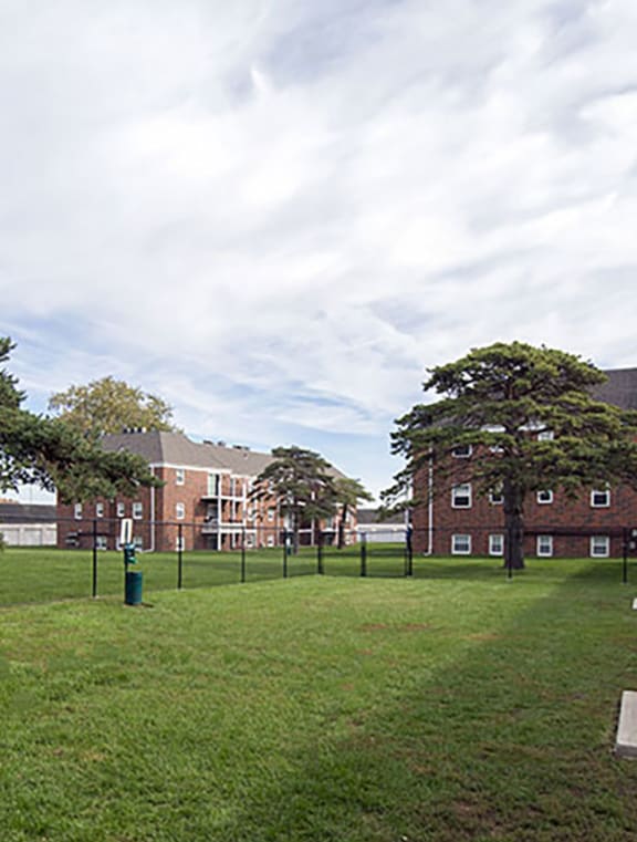 a grassy area with a picnic table in front of a brick building