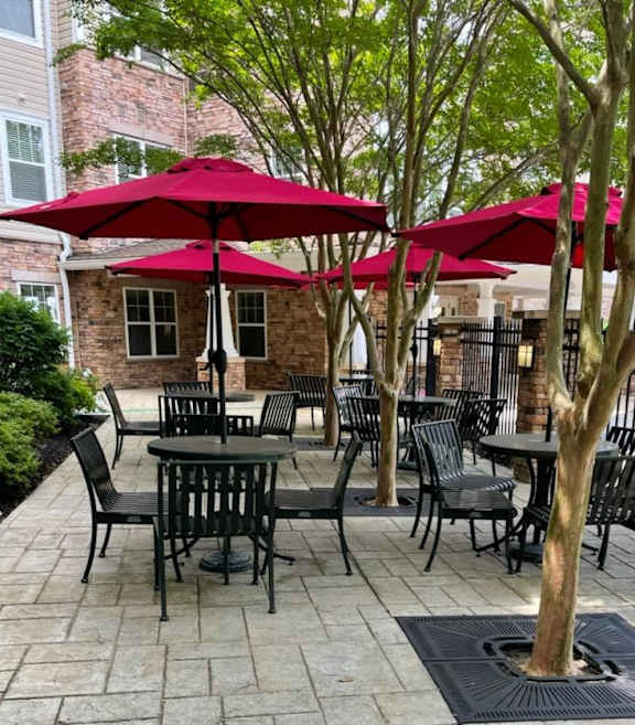 A patio with tables and chairs under red umbrellas.