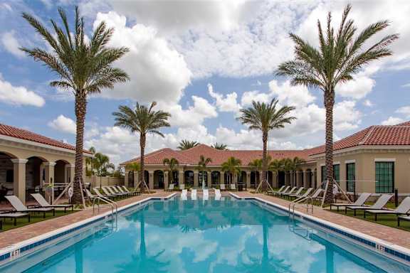 A large swimming pool surrounded by palm trees and lounge chairs.