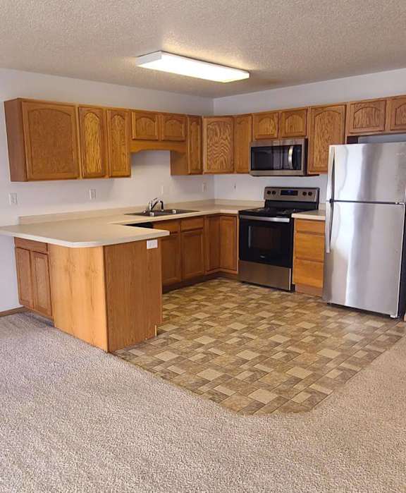 A kitchen with a refrigerator, oven, and sink.