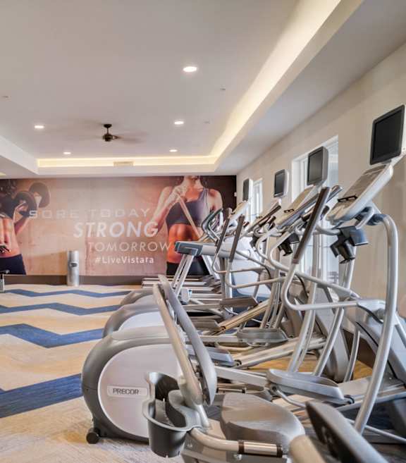 a gym with cardio equipment and weights on the floor