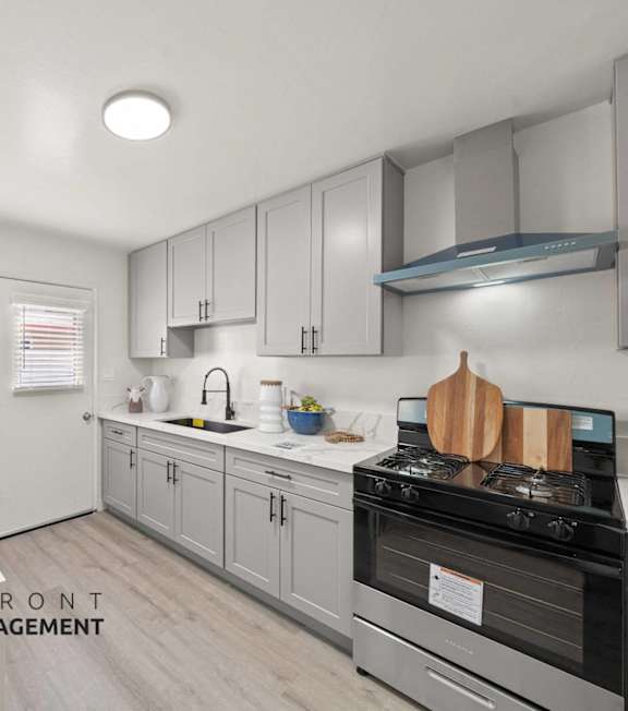 A kitchen with a stove top oven and a dining table with a bowl of fruit on it.