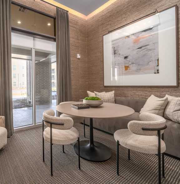 A living room with a table, chairs, and a painting on the wall.