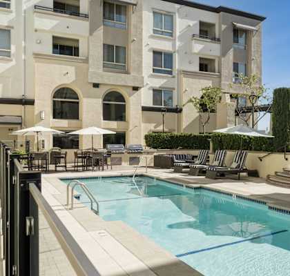 a swimming pool with chairs and umbrellas in front of a building