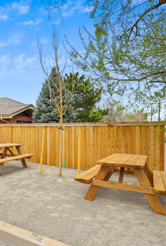 two picnic tables in a fenced in area with a fence