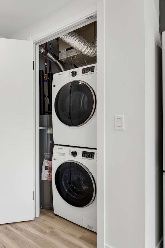 A white kitchen with a refrigerator, oven, and a white couch.