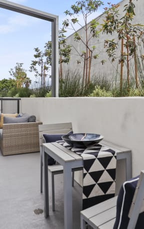 a small balcony with chairs and a table at The Fairfax Flats Apartments, Los Angeles, CA, 90019
