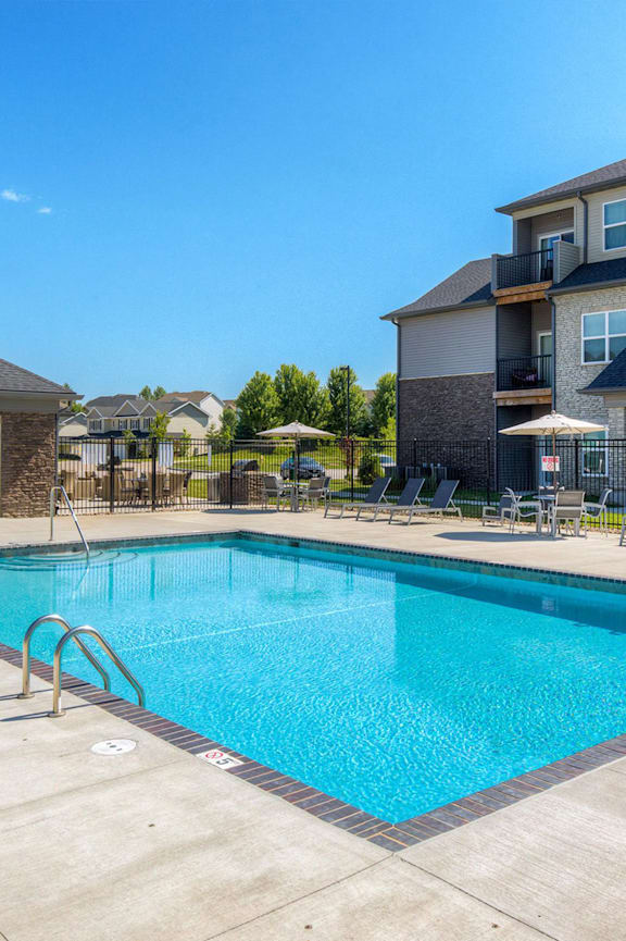 A swimming pool surrounded by a concrete patio and lounge chairs. at Stonegate Crossing Apartments, IOWA, 50325
