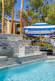 A pool with a slide and a stone wall.