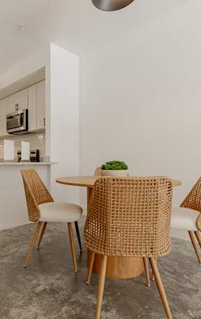 A kitchen with a table and chairs in the foreground and a refrigerator in the background.
