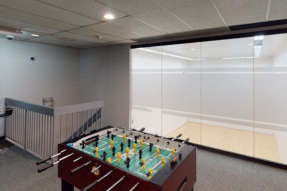 A foosball table is in the middle of a room with a bar stool and a radiator.