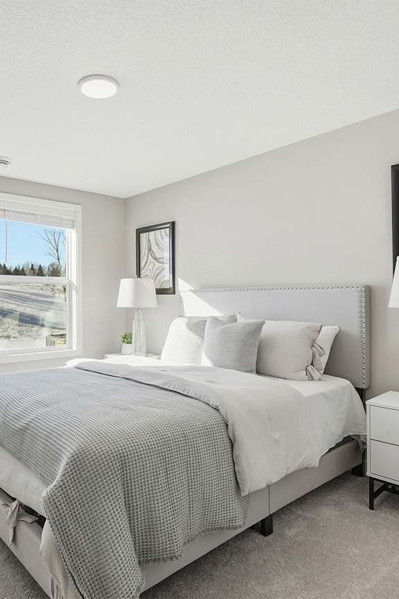 A bedroom with a large bed, a nightstand with a lamp, and a painting on the wall.