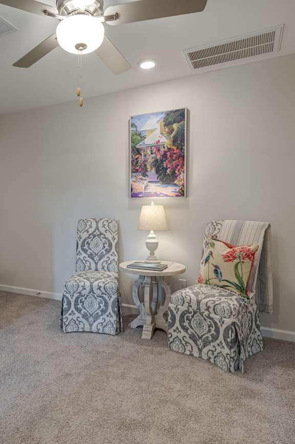 A room with a ceiling fan and a painting on the wall.