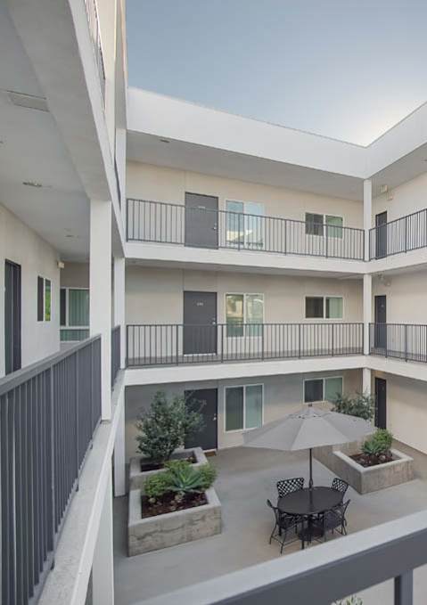 A balcony of a building with a table and chairs and an umbrella at Valley Street Apartment, Los Angeles, CA, 90057