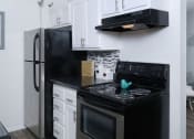 Thumbnail 6 of 23 - Fifteen 50 apartments Las Vegas kitchen with black and silver appliances, white cabinets, and modern black countertops and greyscale tile backsplash