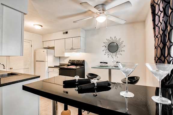 A kitchen with a black refrigerator, stove, and sink.