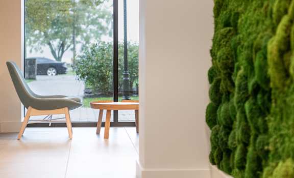 A chair and a small table are in a room with a green wall.