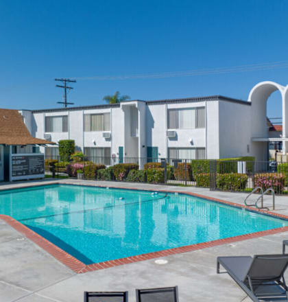 a swimming pool with chairs around it in front of a buildingat The Arches Apartments, LLC, El Cajon California