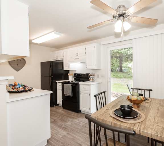 Dining area attached to the kitchen with white cabinets, next to a clear sliding door with an outdoor view.