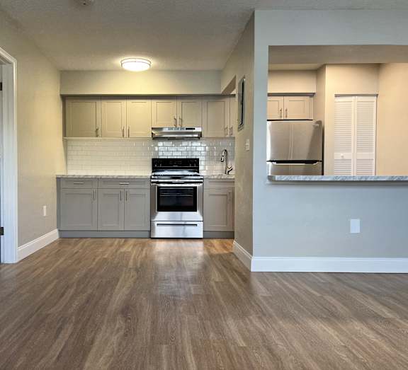 A kitchen with a white tile backsplash and wooden floors.