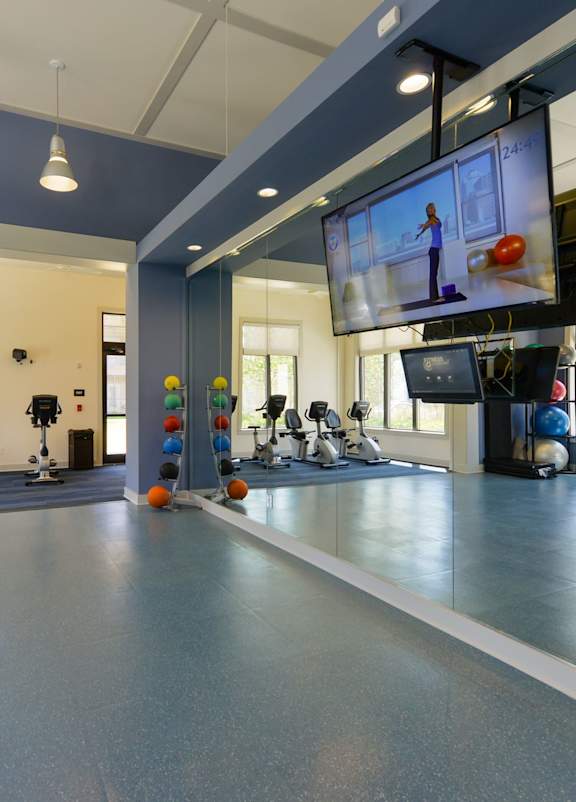 A gym with a blue floor and a television mounted on the wall.