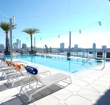 A pool with chairs and a view of the city.